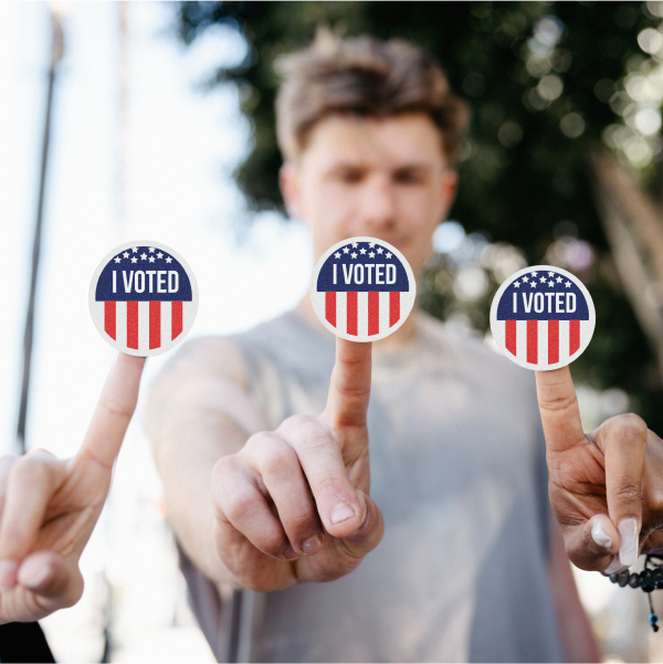 Two women and a man holding out an “I Voted” sticker on the tip of each of their fingers.