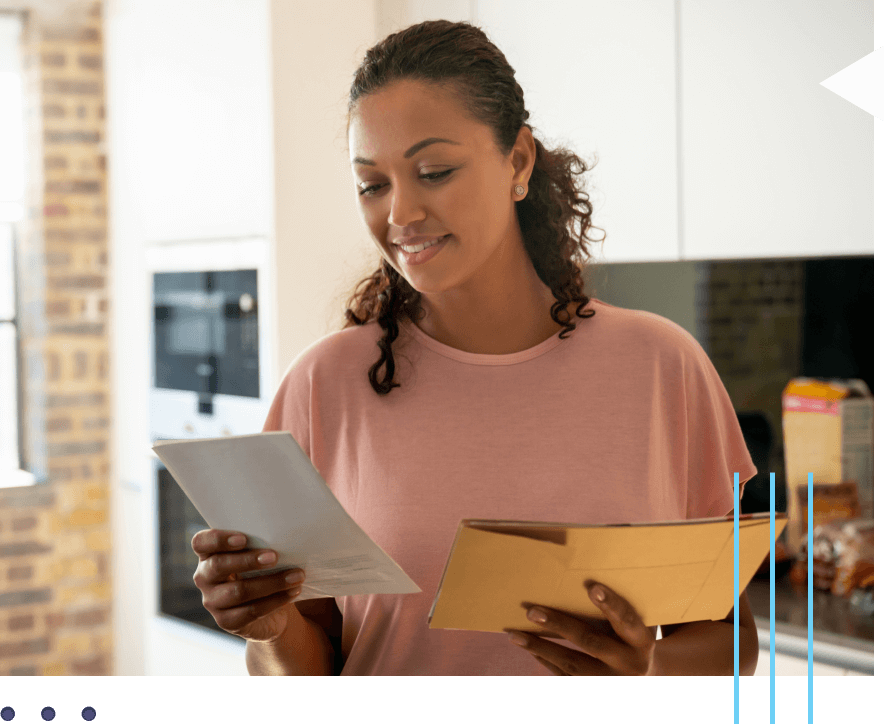 A woman smiles as she reads her mail