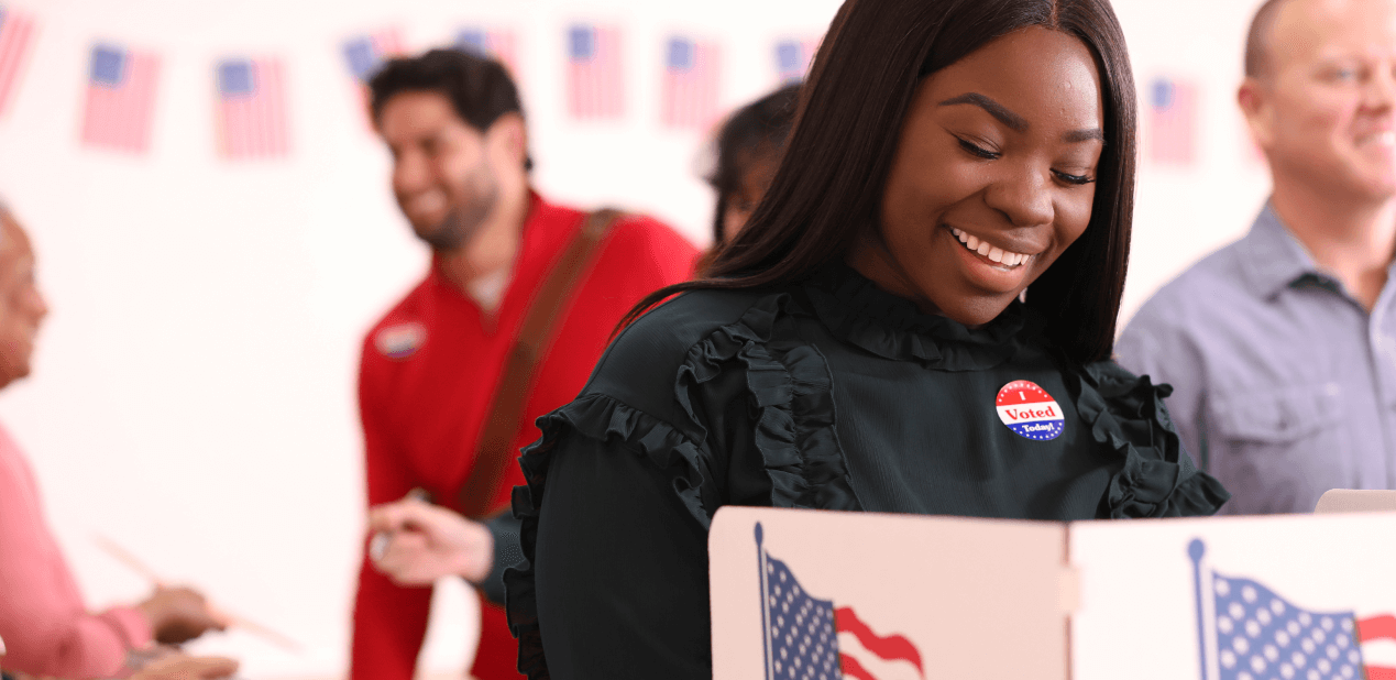 Woman smiling while casting a vote in a booth.